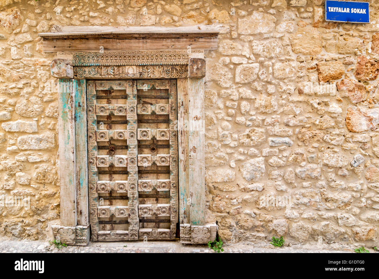 NORTH CYPRUS KYRENIA OLD TOWN CARVED WOODEN DOOR AND OLD STONE WALL WITH STREET SIGN TAYFALAR SOKAK Stock Photo