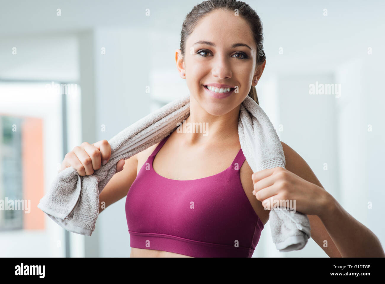 Beautiful sporty woman with towel relaxing at the gym after working out ...