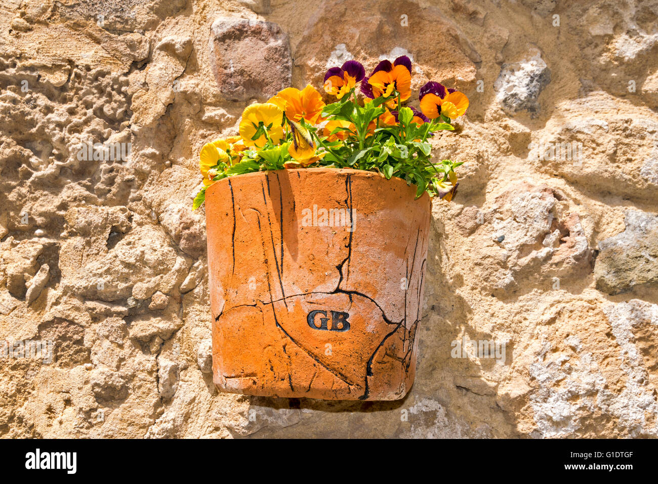 NORTH CYPRUS KYRENIA OLD TOWN TERRACOTTA POT ON AN OLD STONE WALL FILLED WITH ORANGE PETUNIA FLOWERS Stock Photo