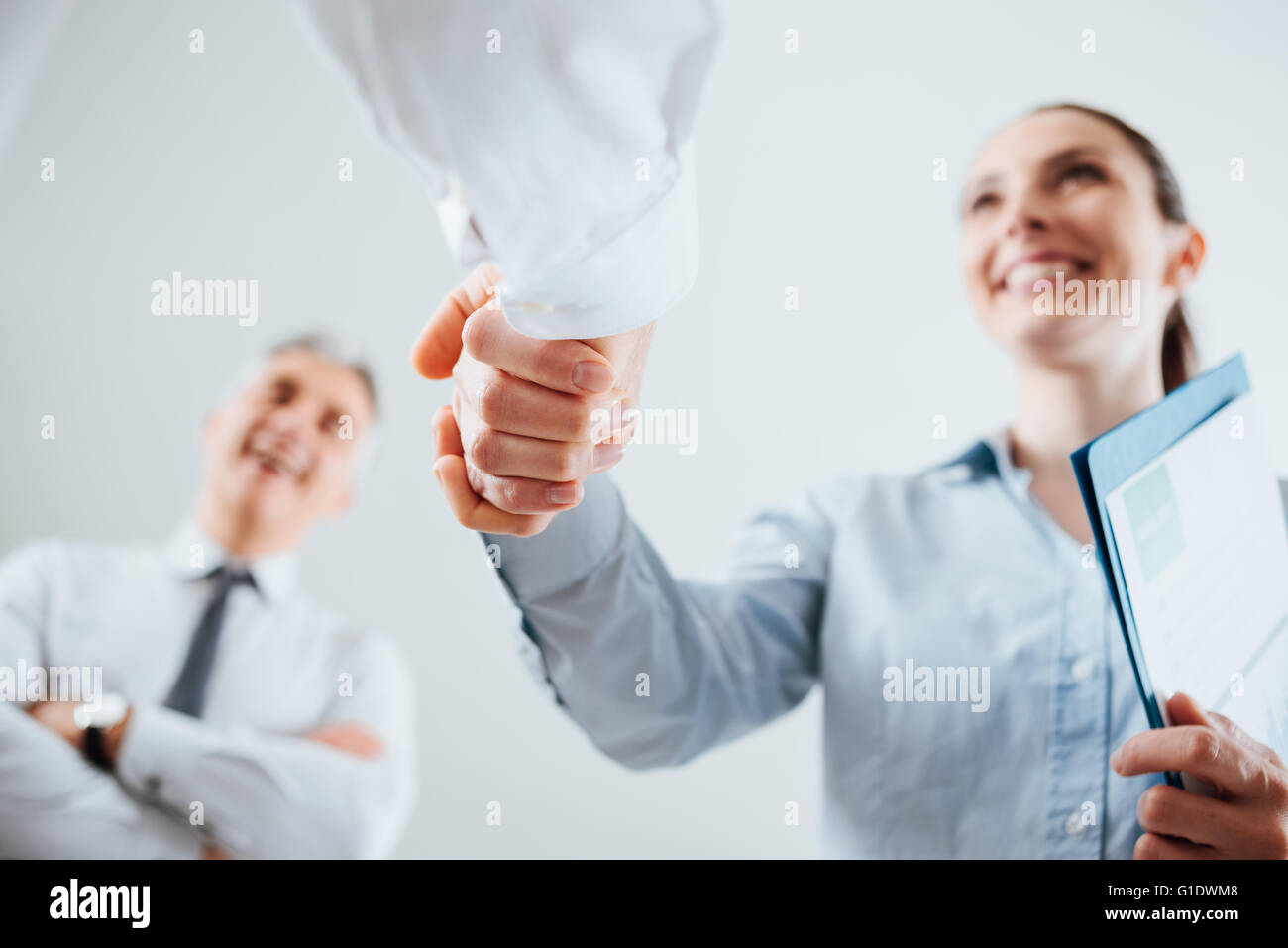 Confident business people shaking hands and woman smiling, recruitment and agreement concept Stock Photo