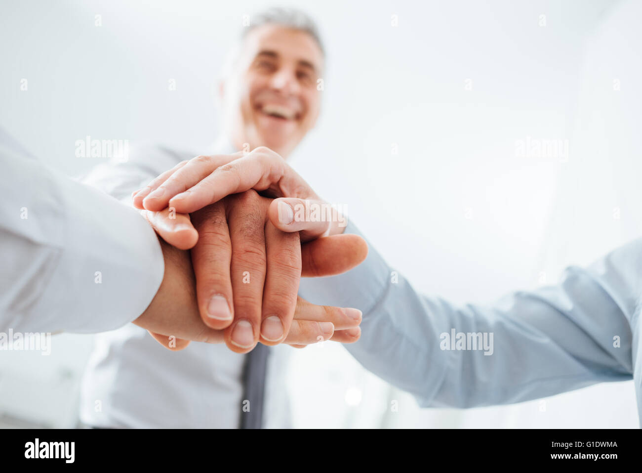 Cheerful business team stacking hands and smiling, teamwork and success concept, hands close up Stock Photo