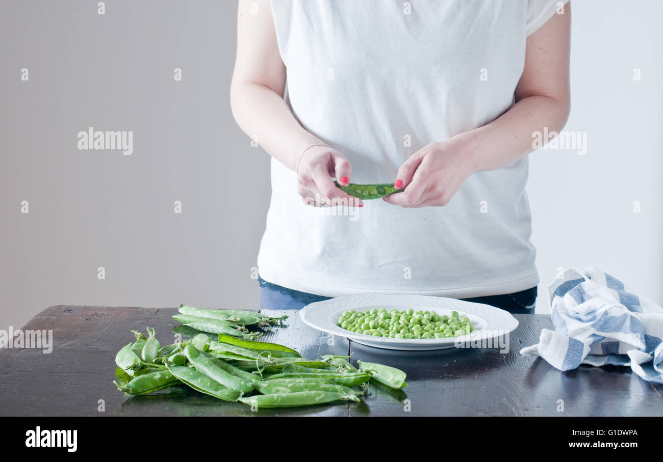 young woman peeling green fresh peas,italy Stock Photo