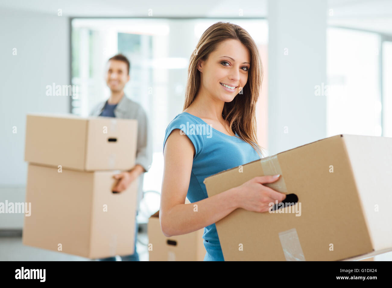 Happy smiling couple moving in a new house and carrying carton boxes, relocation and renovation concept Stock Photo