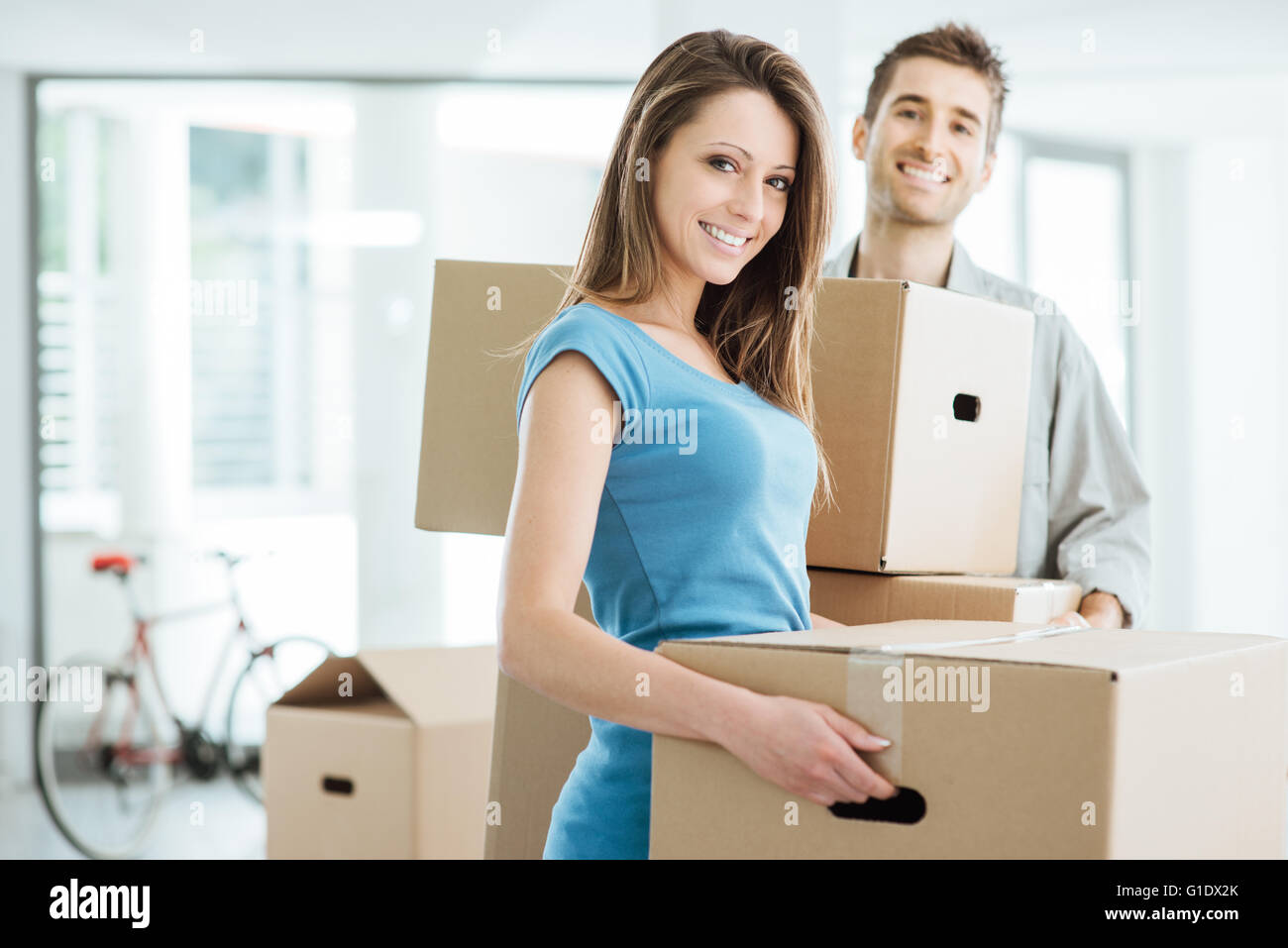 Happy smiling couple moving in a new house and carrying carton boxes, relocation and renovation concept Stock Photo