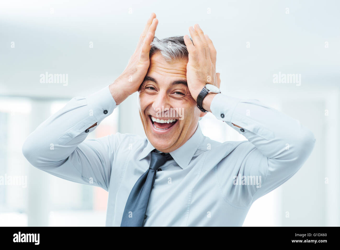 Cheerful careless businessman laughing and touching his forehead Stock Photo