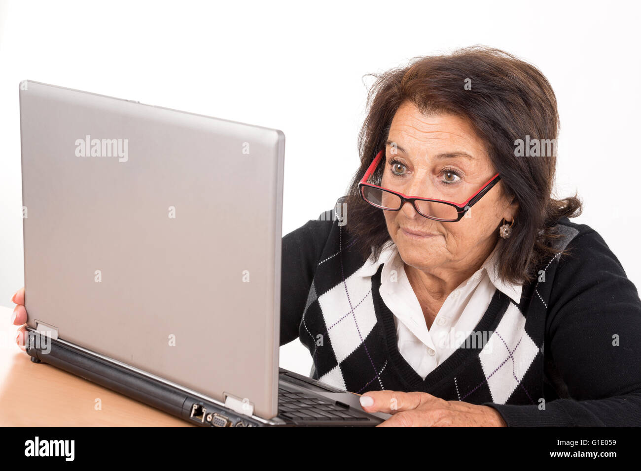 Surprised beautiful senior woman looking at a laptop isolated in white Stock Photo