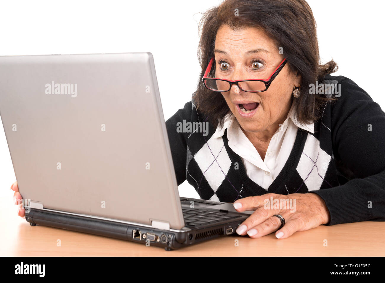 Surprised beautiful senior woman looking at a laptop isolated in white Stock Photo
