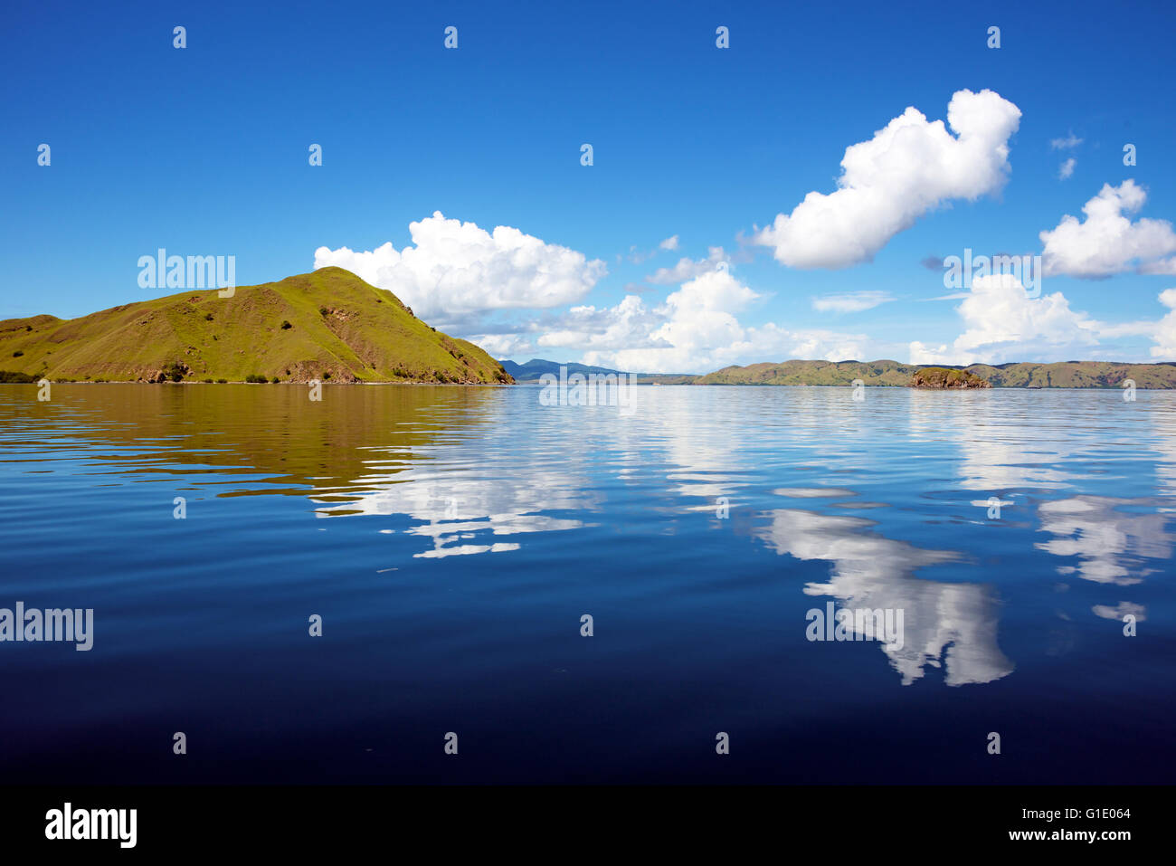 Clouds over Pengah Island reflected in calm sea Komodo National Park Indonesia Stock Photo