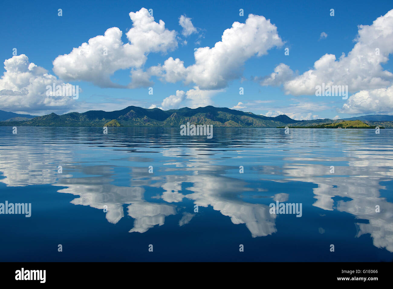 Clouds over Rinca Island reflected in calm sea Komodo National Park Indonesia Stock Photo