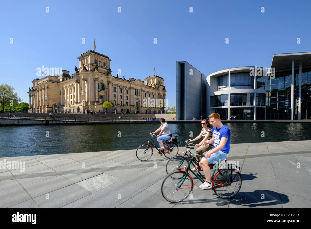 View of the Reichstag Parliament building and tourists on bicycles beside  River Spree in Berlin Germany Stock Photo