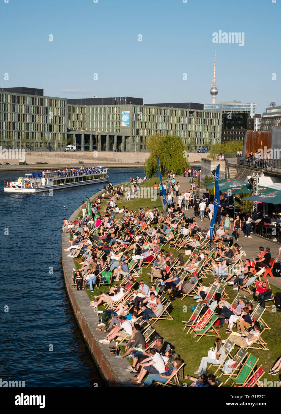 People sitting in afternoon beside River Spree at outdoor bar in Berlin Germany Stock Photo