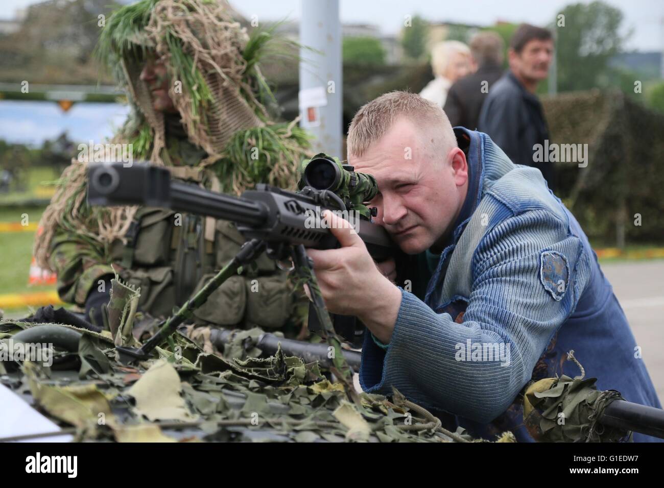 Vilnius, Lithuania. 14th May, 2016. A man is experiencing a sniper rifle in Vilnius, Lithuania, May 14, 2016. Lithuania celebrates Armed Forces and Public Unity Day in it's captial on Saturday. Troops of Lithuania, Germany, U.S., Luxembourg, Portugal, etc. brought their light weapons, military vehicles and other equipment to the public. Fighting Falcon F-16 of Portuguese air force and Black Hawk of the U.S. air force participated in the performance. Credit:  Bu Peng/Xinhua/Alamy Live News Stock Photo