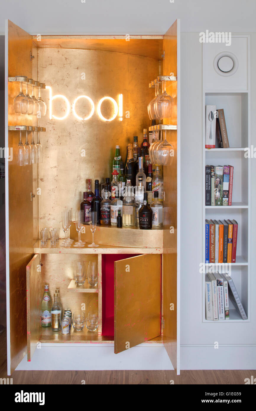 Modern Family home, Shepherds Bush, London. Close view of a drinks cabinet with bottles of alcohol. Gold leaf background. Stock Photo