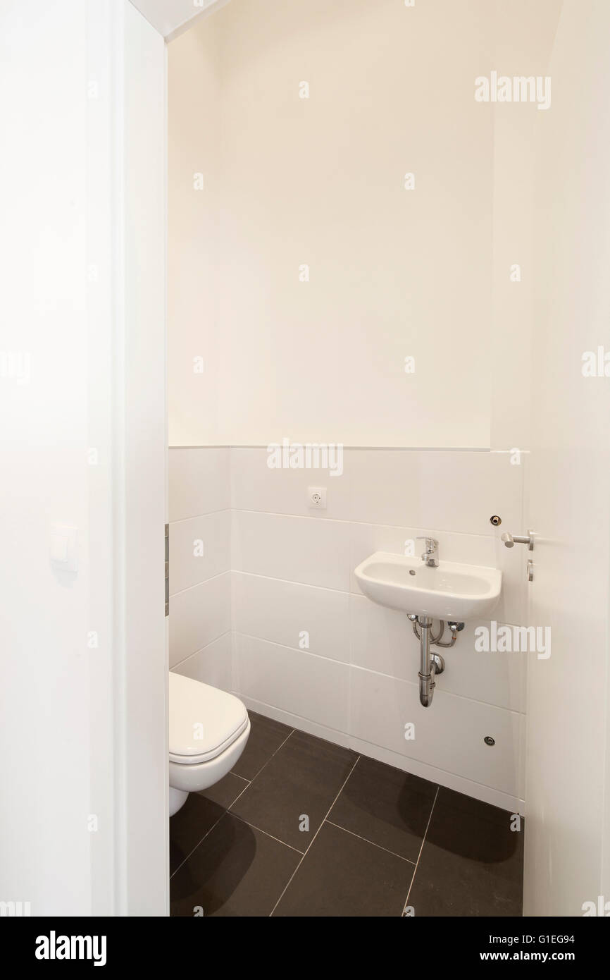 Buro, 53 Reichenberger Strasse. Small bathroom with white toilet and sink and black tiling. Stock Photo