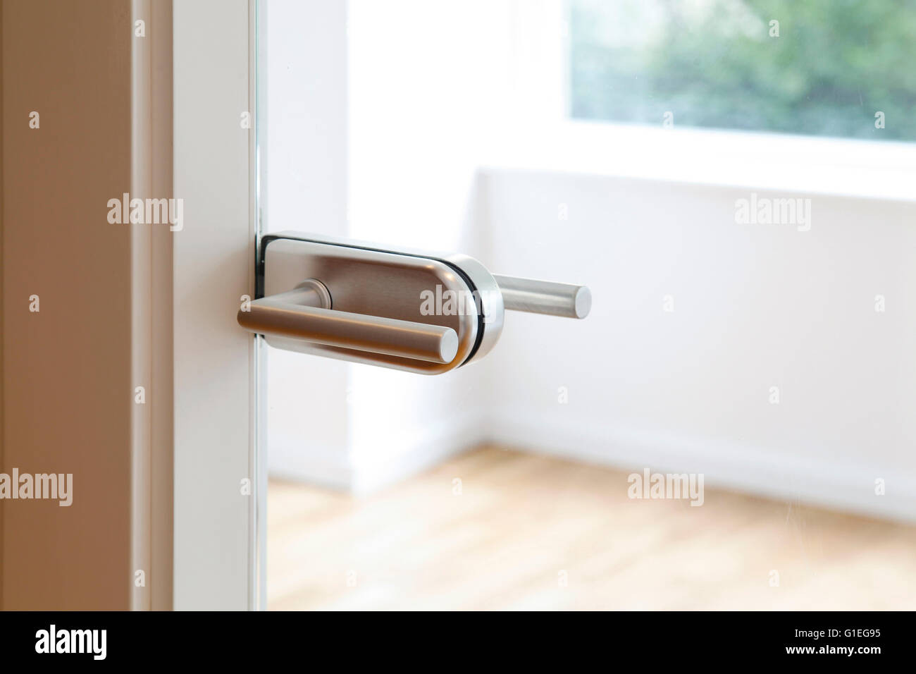 A stainless steel doorknob on a glass door. Stock Photo