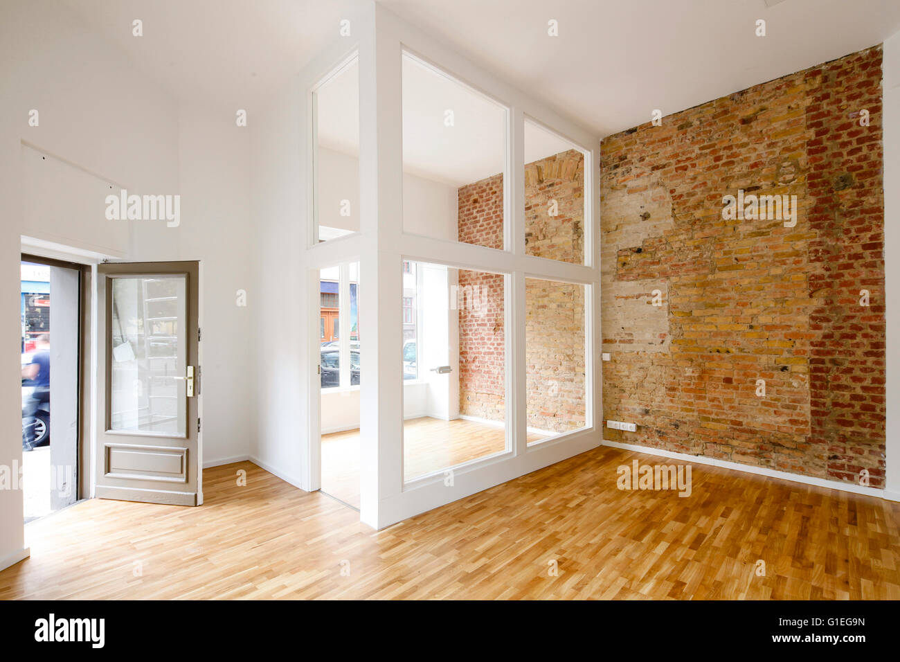 Buro, 53 Reichenberger Strasse. Spacious room with modern layout and exposed brick wall. Open front door with glass partition. Stock Photo