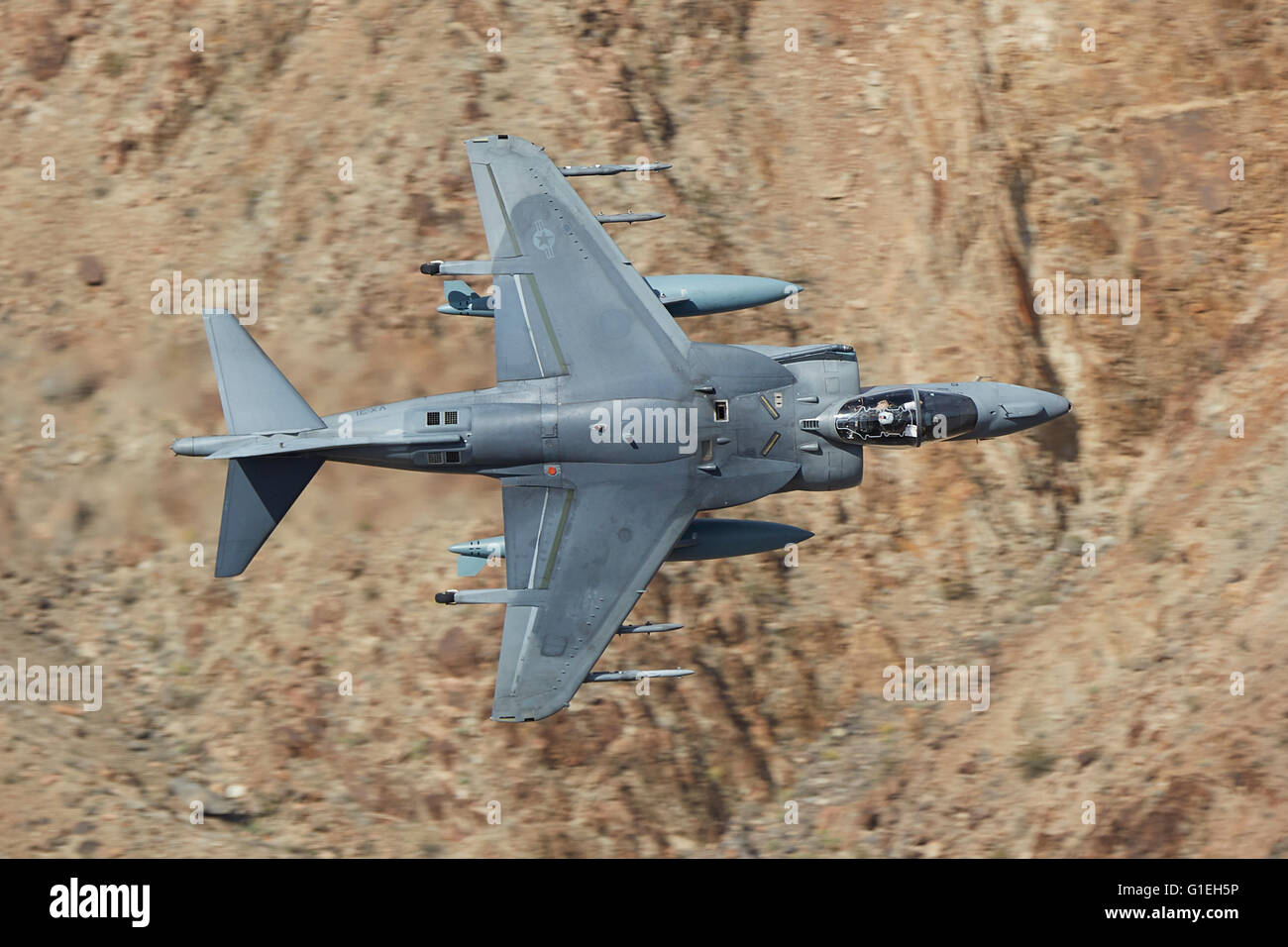 United States Marine Corps AV-8B Harrier II V/STOL Ground Attack Jet Flying At Low Level And High Speed Through A Desert Valley In California, USA. Stock Photo