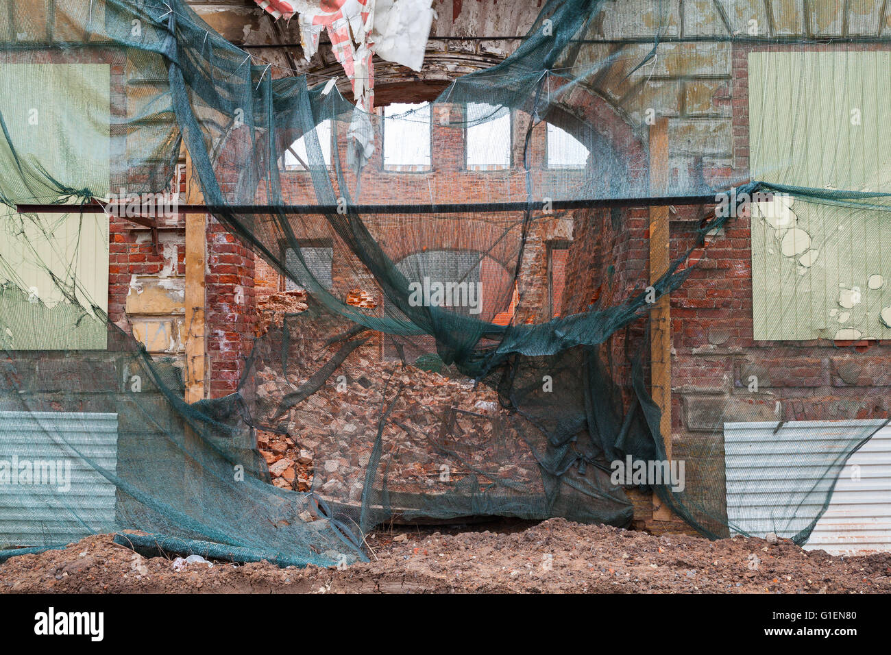 Old living house is under reconstruction, facade with arch is covered with green protection mesh Stock Photo