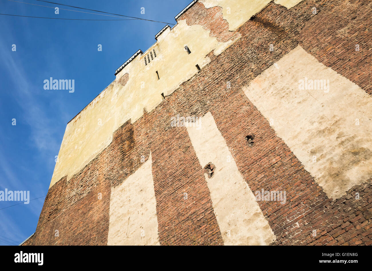 Old brick wall of abandoned house with damaged plastering layer under blue sky. St. Petersburg, Russia Stock Photo