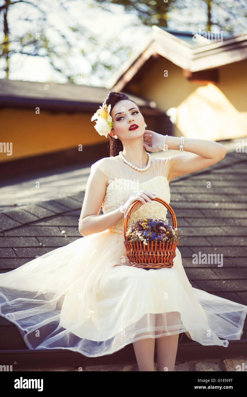Woman in vintage dress holding a basket with flowers Stock Photo