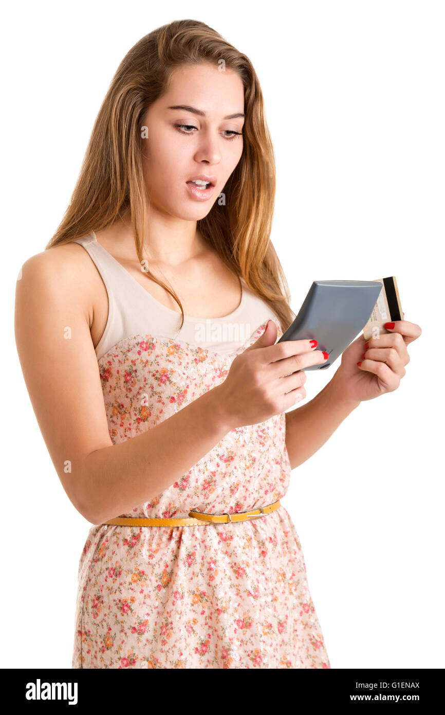 Worried woman looking at a calculator and holding a credit card, isolated in white Stock Photo