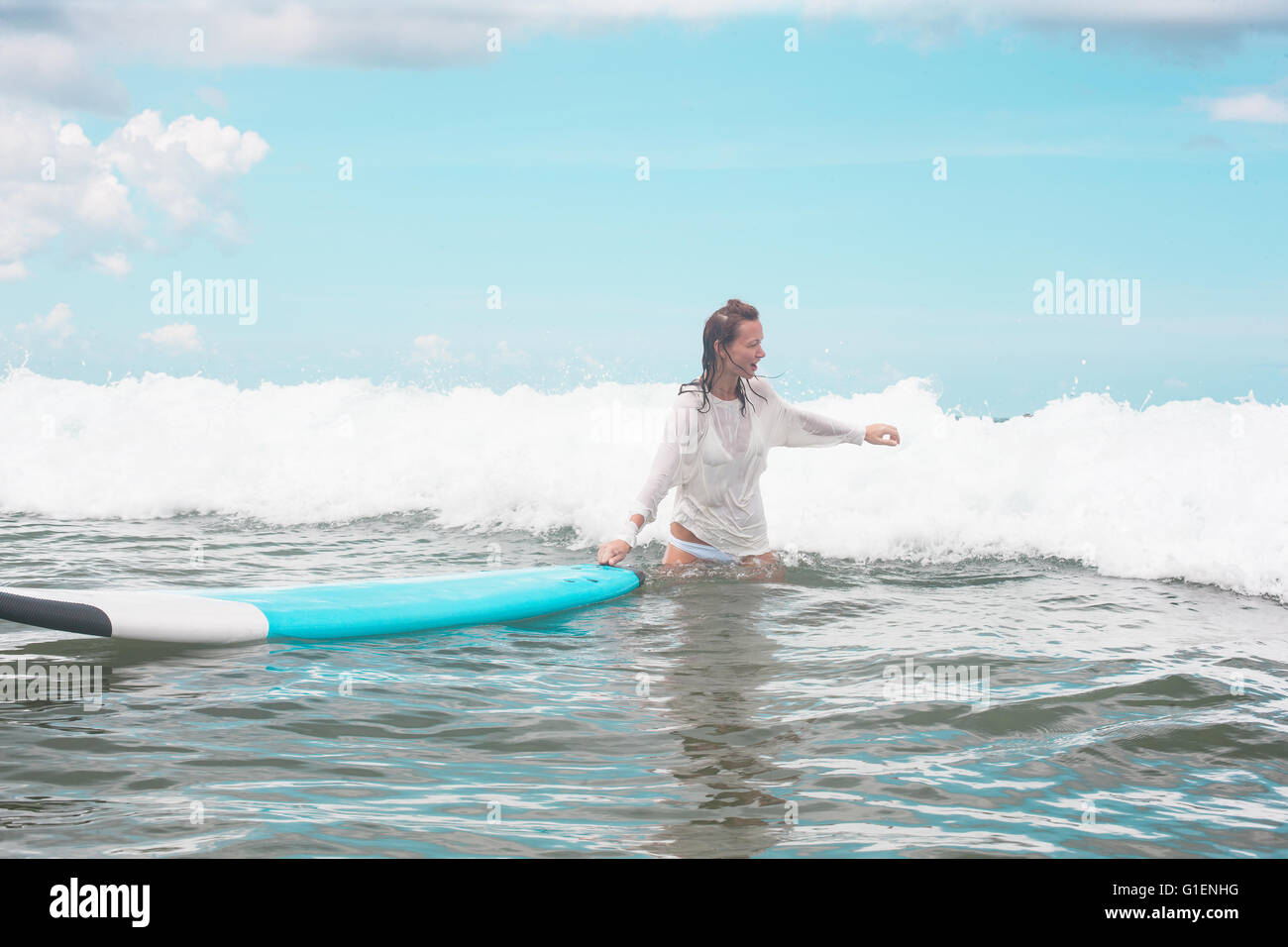 Girl on the waves with surfboard. Stock Photo