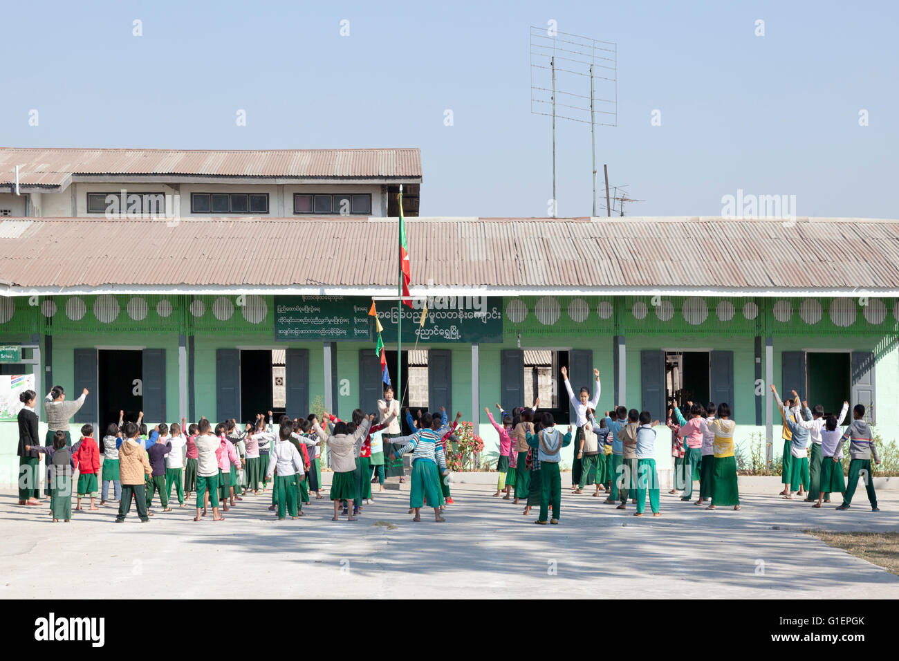 Before class, the pupil physical training in a primary school of Nyaungshwe (Myanmar). La culture physique matinale des élèves. Stock Photo