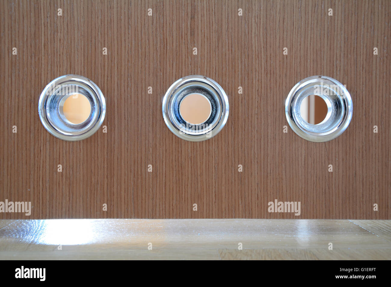 Round silver vents in brown wooden bathroom door. Stock Photo