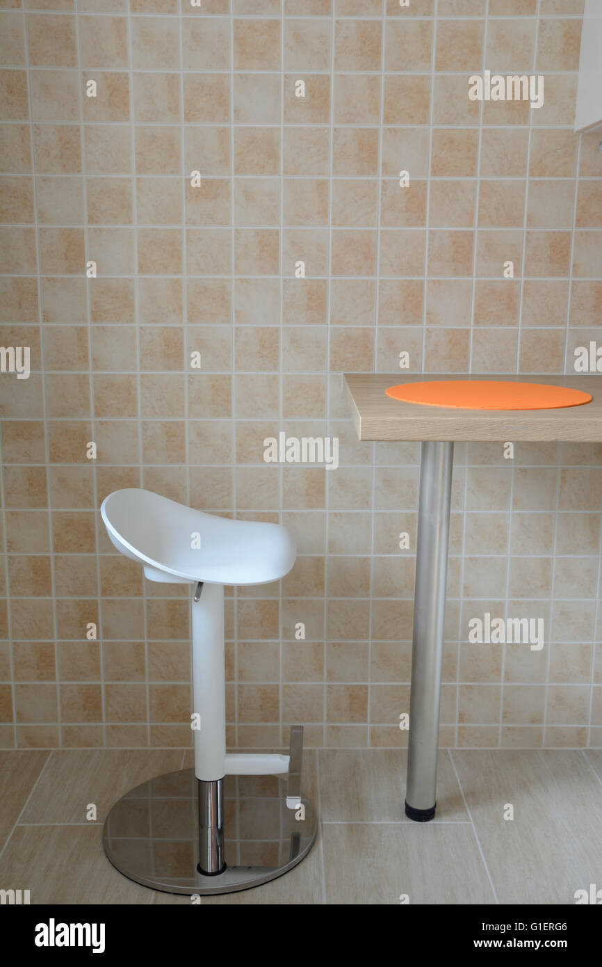 White swivel stool and kitchen small table with orange rubber tablemat