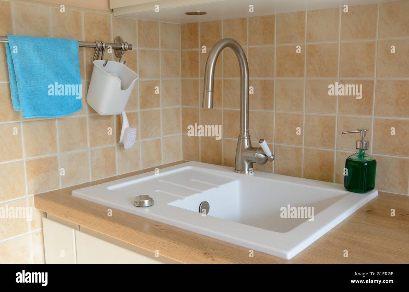 Kitchen sink, tap and other items on brown wooden kitchen counter Stock