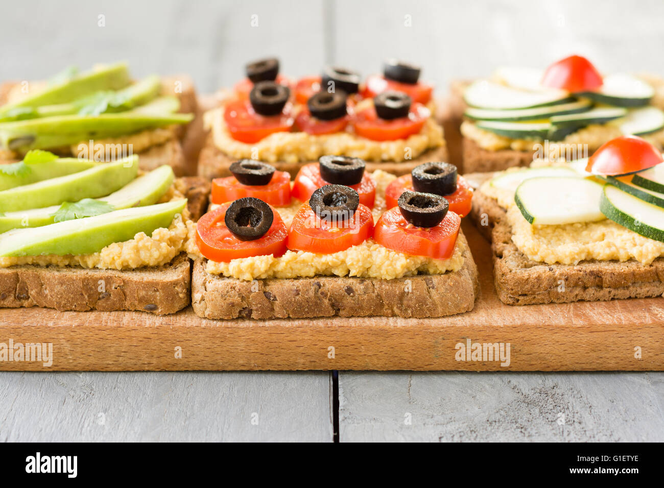 Hummus Toasts with zucchini and a cherry tomato, cherry tomato and black olives and avocado. Stock Photo