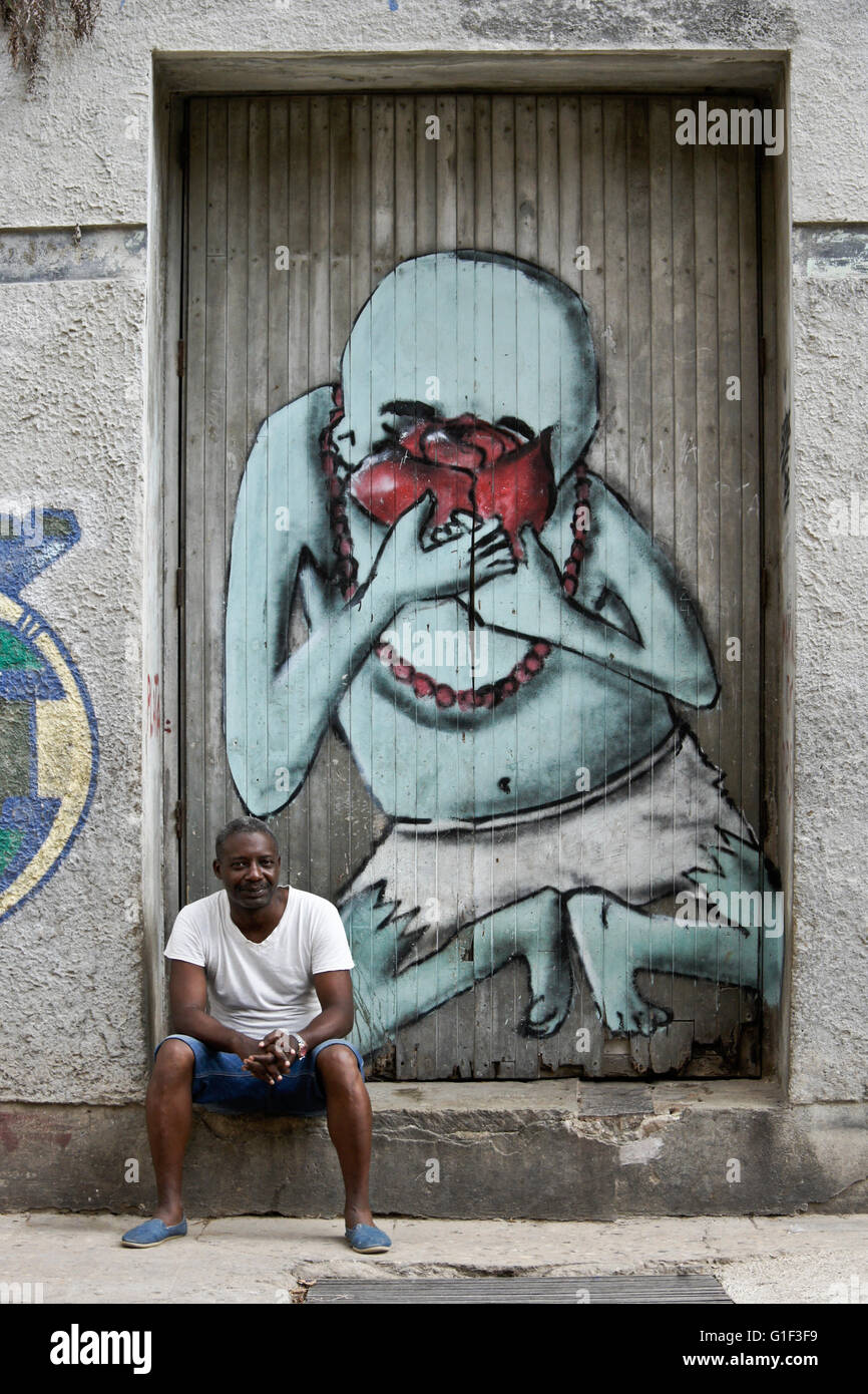 Man sitting on step in front of street art, Havana, Cuba Stock Photo