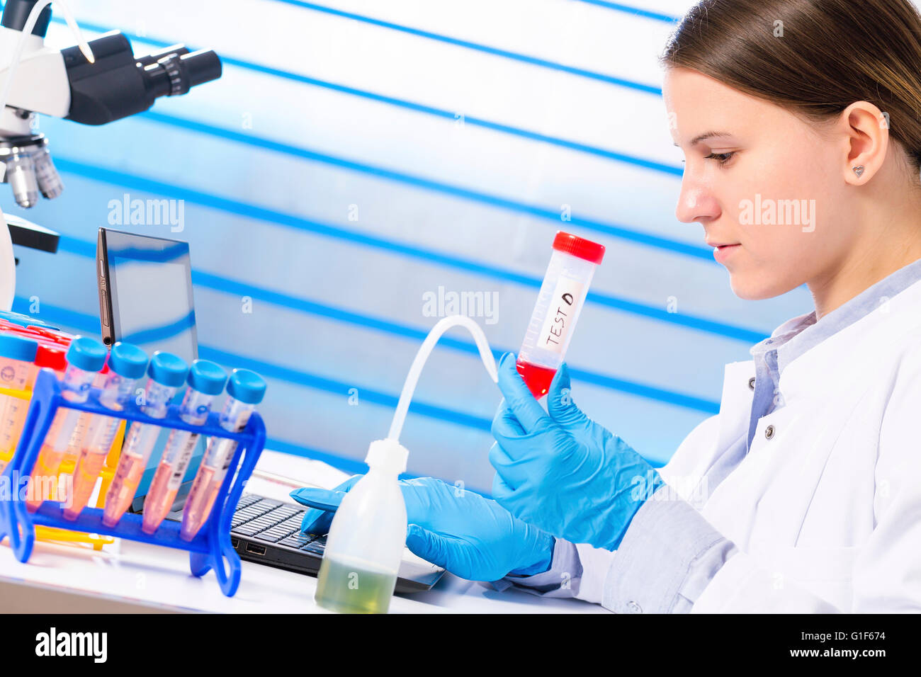 MODEL RELEASED. Female lab technician holding test tube in laboratory ...