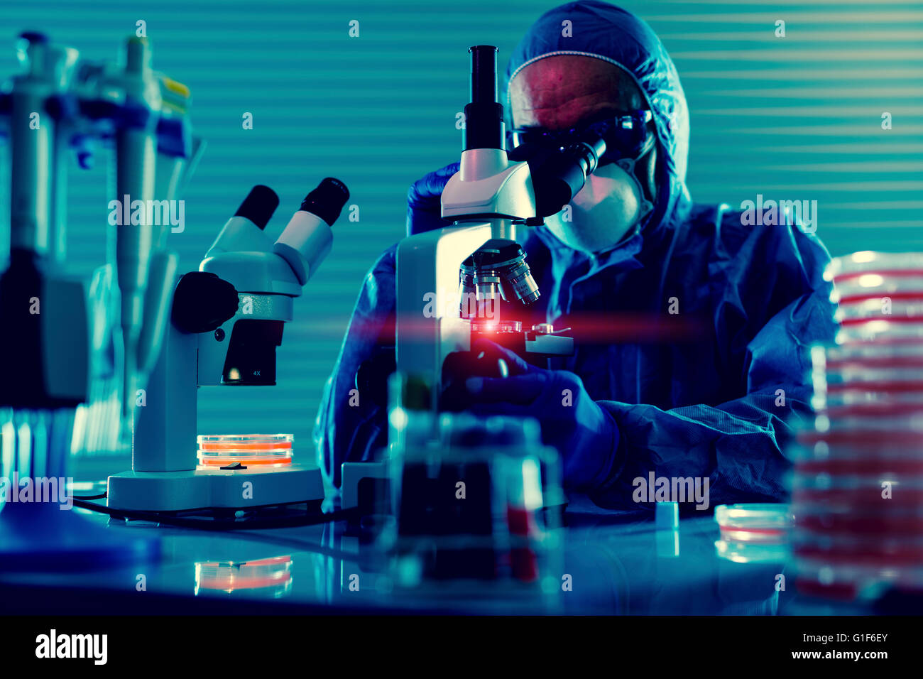 MODEL RELEASED. Person wearing protective clothing using microscope in