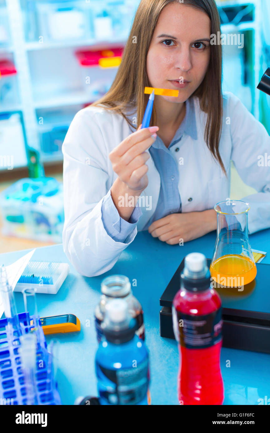 MODEL RELEASED. Female scientist testing food samples in a flask. Stock Photo