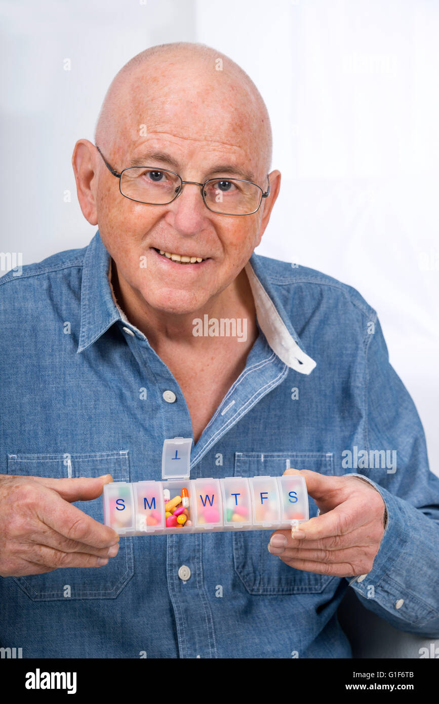 MODEL RELEASED. Senior man holding a pill organiser. Stock Photo
