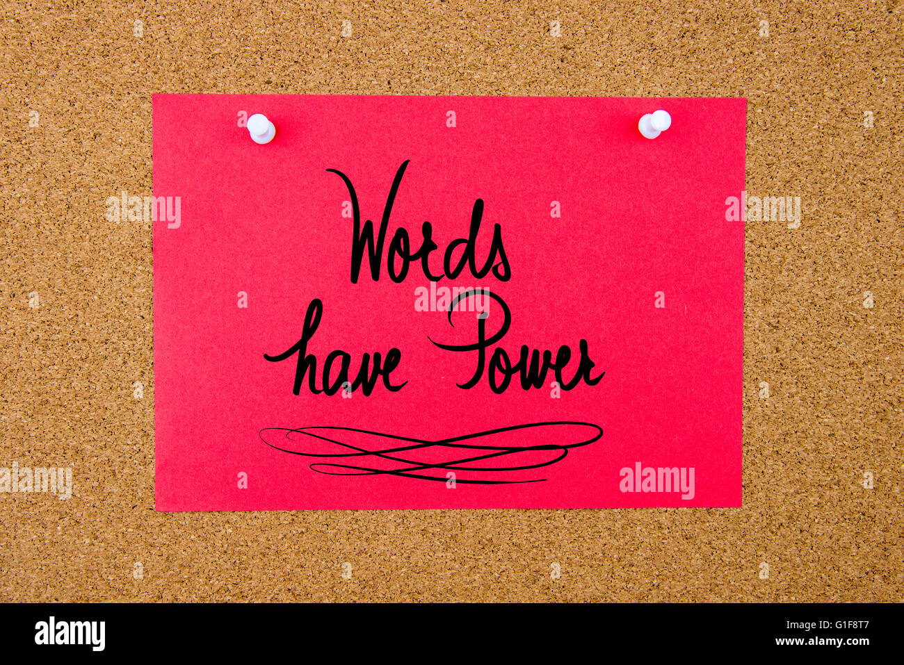 Red paper note with handwritten text Words Have Power pinned on cork board with white thumbtacks Stock Photo