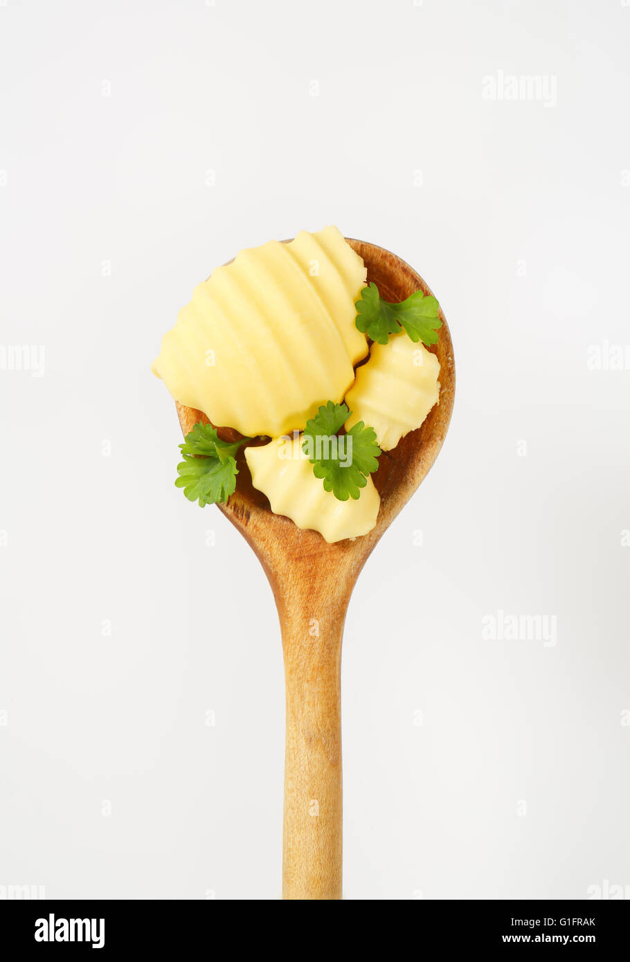 butter curls and fresh parsley on wooden spoon Stock Photo