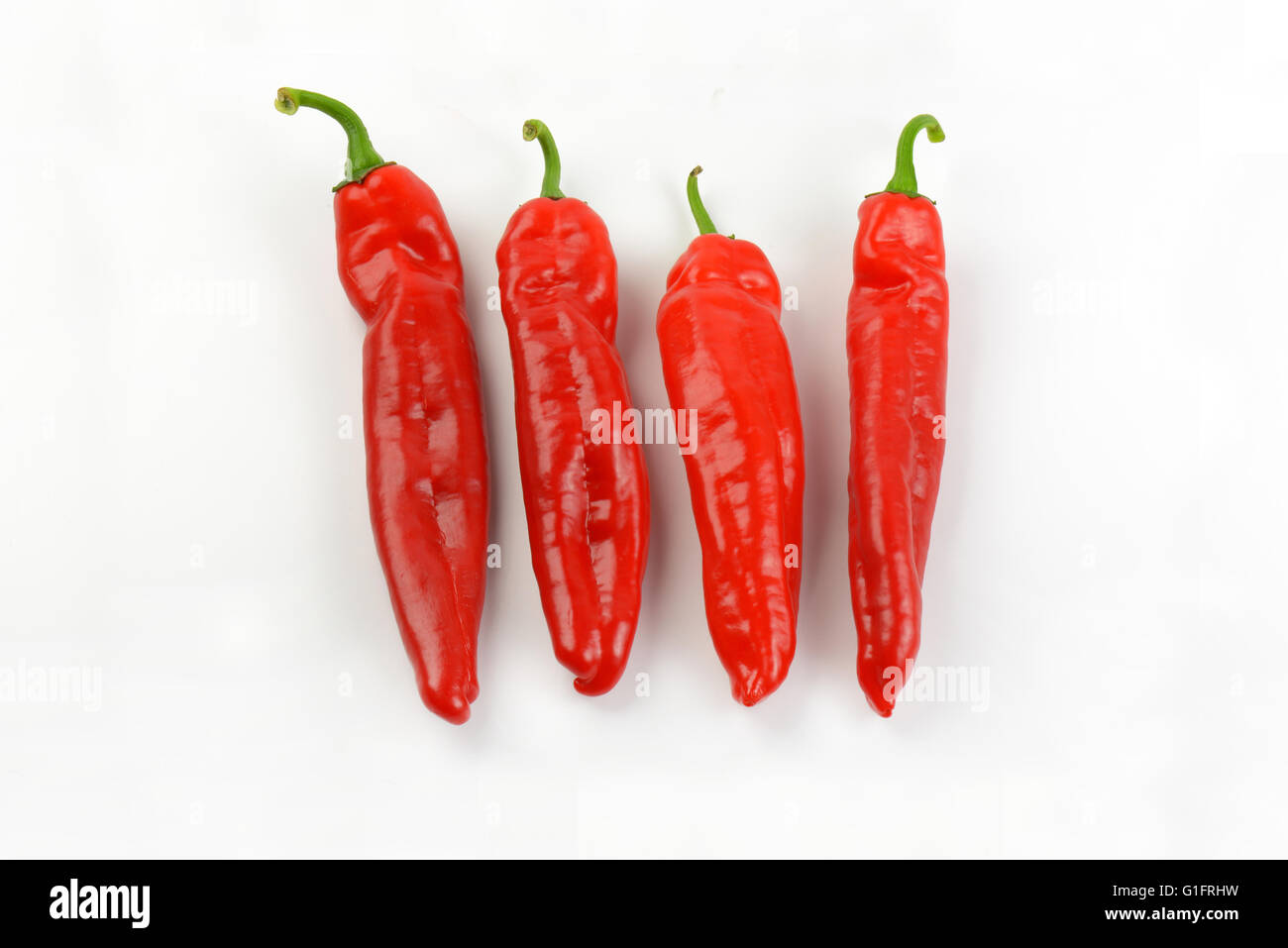 four red peppers on white background Stock Photo - Alamy