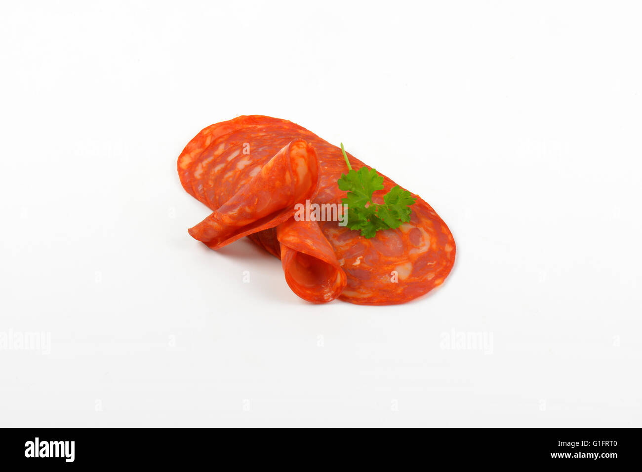 slices of chorizo salami with parsley on white background Stock Photo