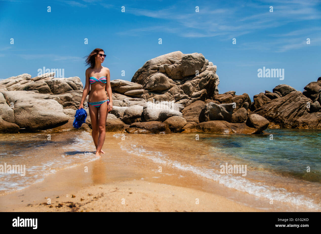 Girl in swimsuit walks along the wild beautiful beach in Vourvourou, Sithonia, Greece Stock Photo
