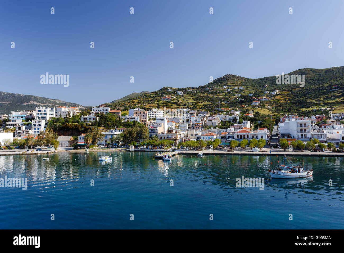 Marmari port with anchored fish boats against a blue sky and blue waters in Evia, Greece Stock Photo