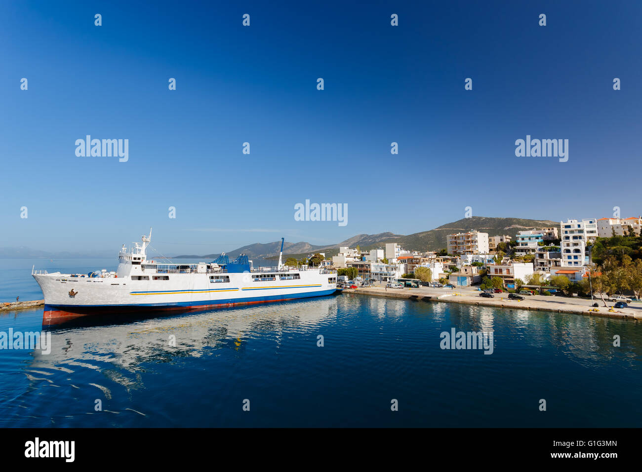 Marmari port with anchored ship against a blue sky and blue waters in Evia, Greece Stock Photo