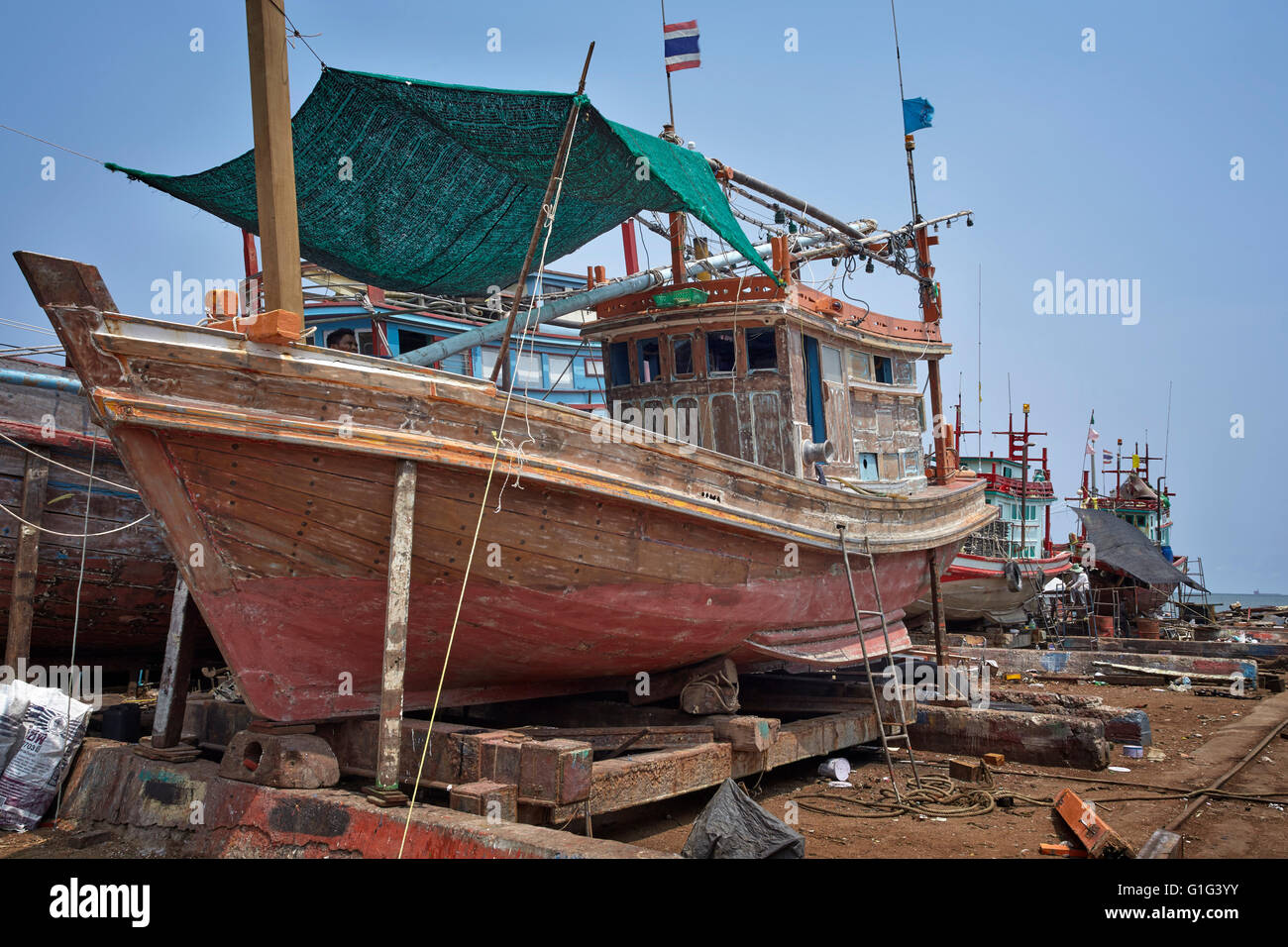 Traditional Thai wooden commercial fishing boat undergoing repair