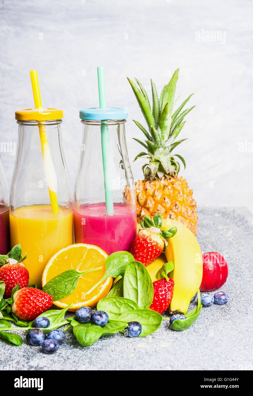 Red and yellow smoothies drinks in bottles with fruits ingredients on light background. Healthy lifestyle, Detox or diet food co Stock Photo
