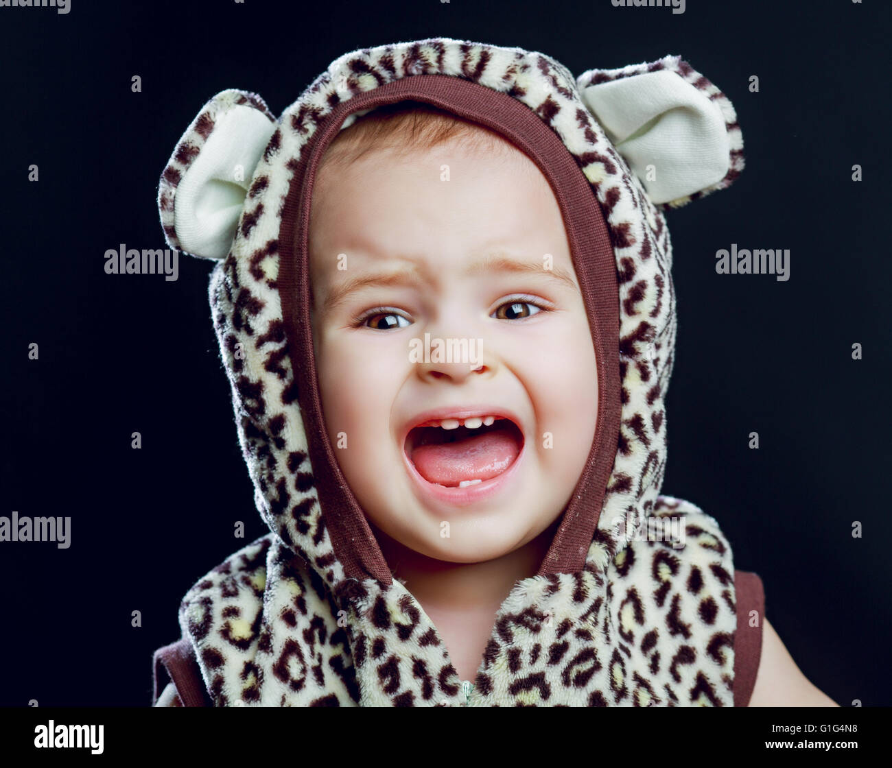 unhappy crying one year old baby, isolated against black background