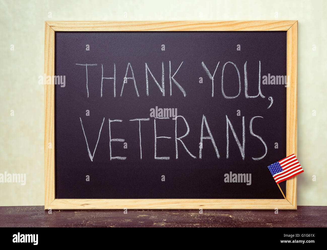 handwriting text thank you veterans is written in chalkboard with flag of United States on rustic wooden background, instagram s Stock Photo