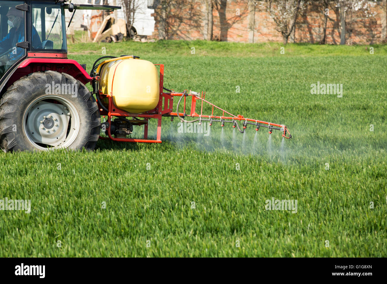 Spraying wheat crops field with tractor and sprayer Stock Photo