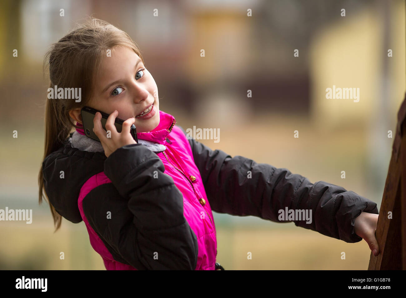 Cheerful little girl talking on a mobile phone call. Stock Photo