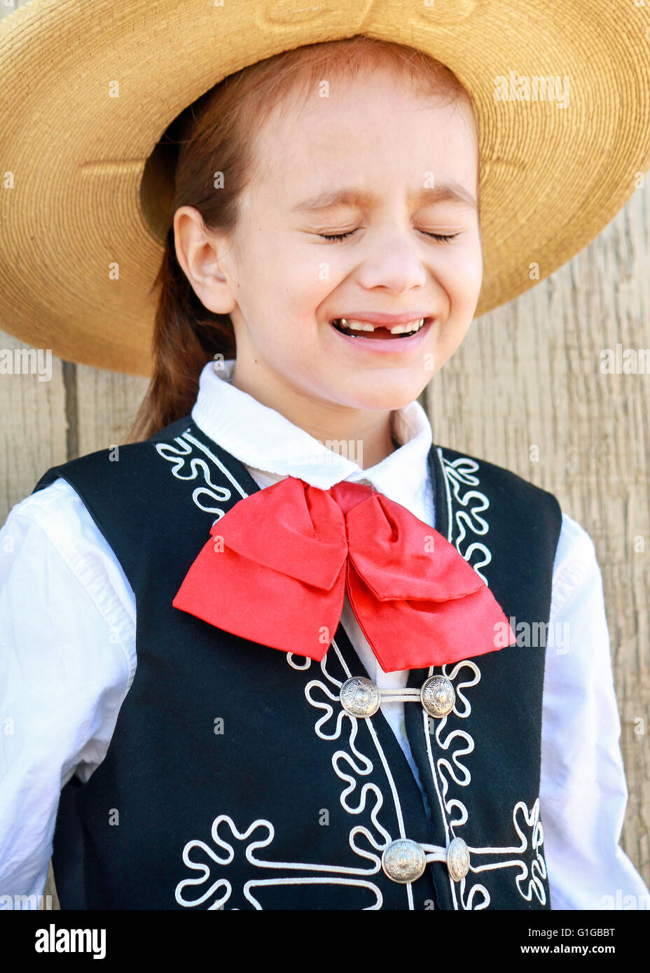 Young boy dressed up in Mexican folklorico outfit squinting from the sun. Stock Photo